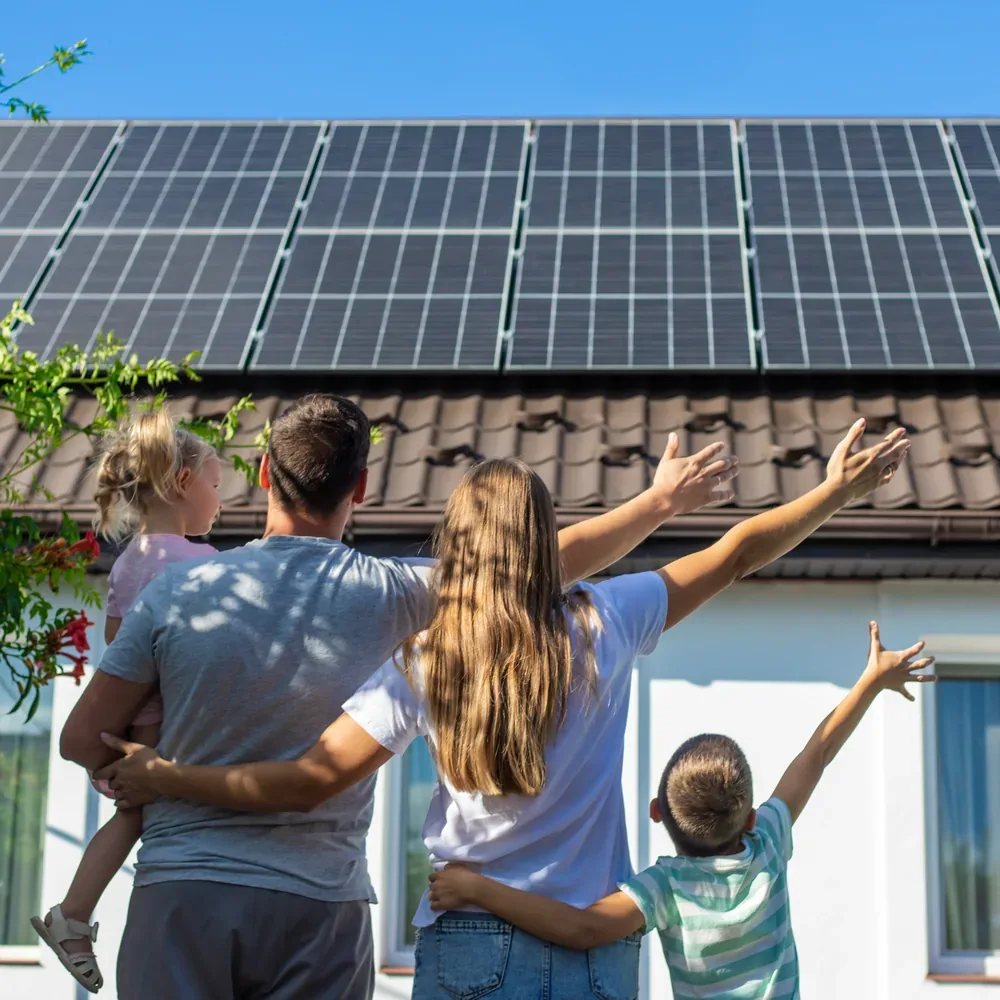 A family looking up at solar panels on the roof of their home